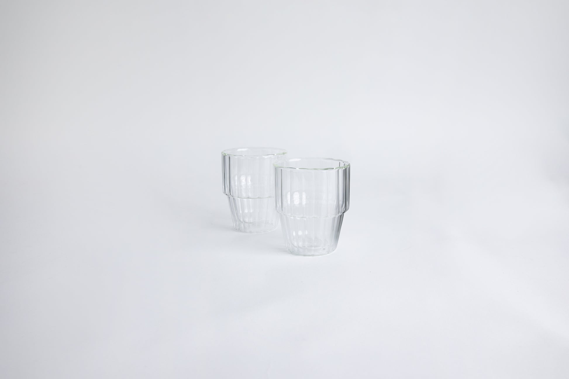 2 ribbed clear glass cup on a white background