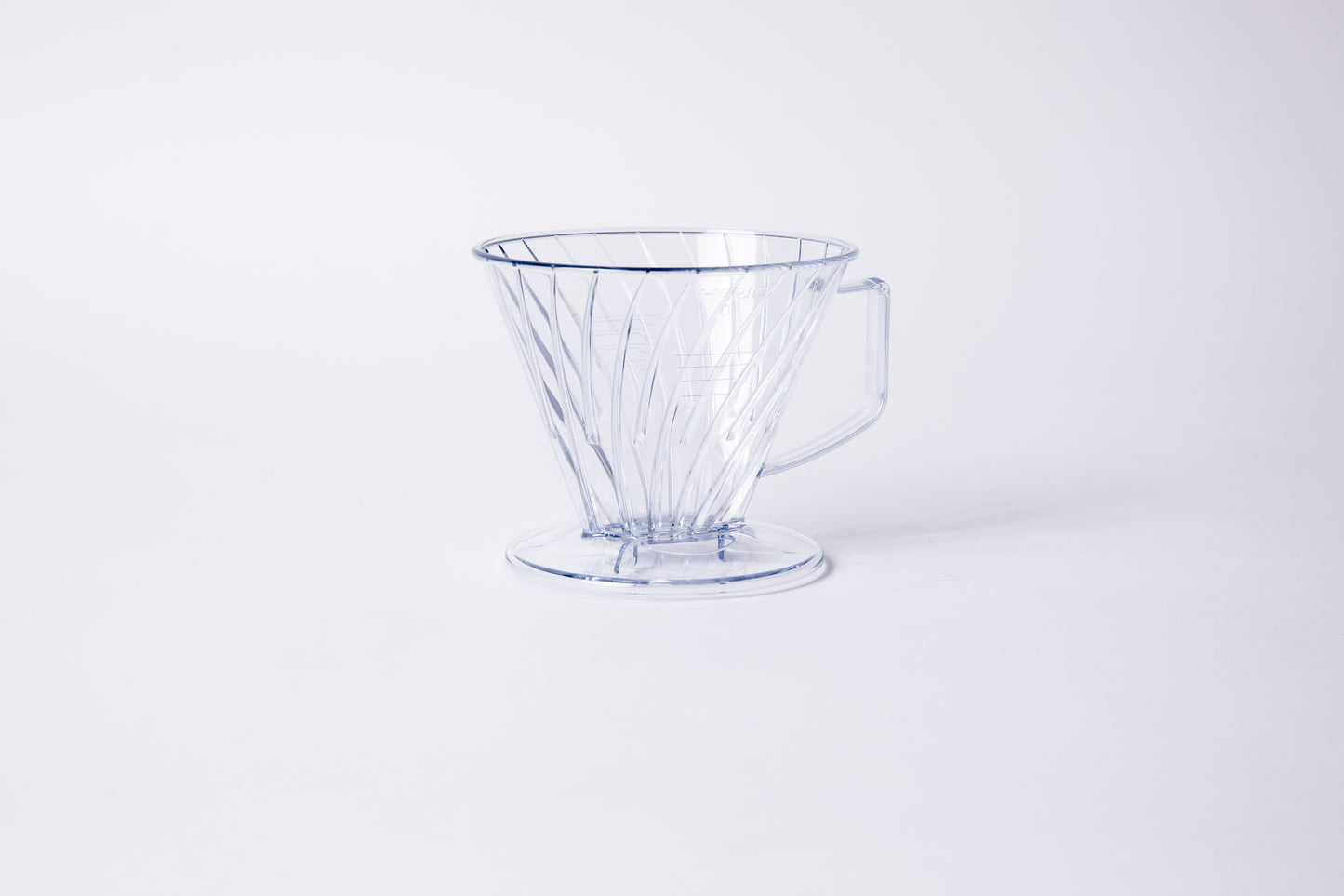 Clear plastic ribbed cone shaped dripper with a flat bottom base and handle. Set on a light gray background