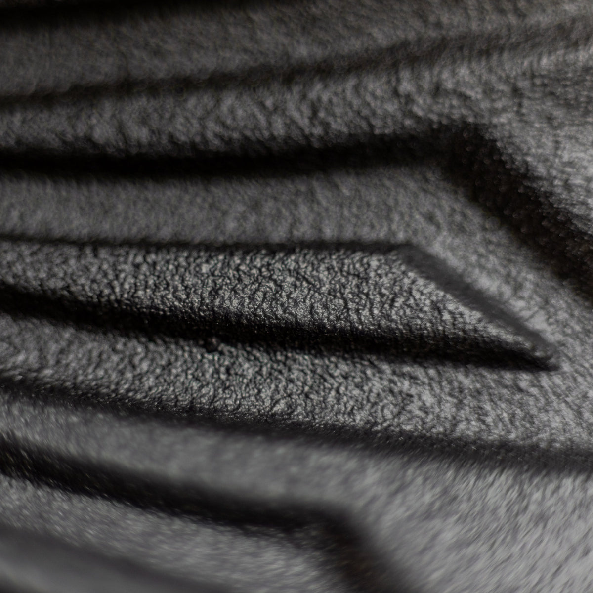 Close-up of a dark textured surface with a repeating geometric pattern and grooved lines, likely a material or finish detail shot.