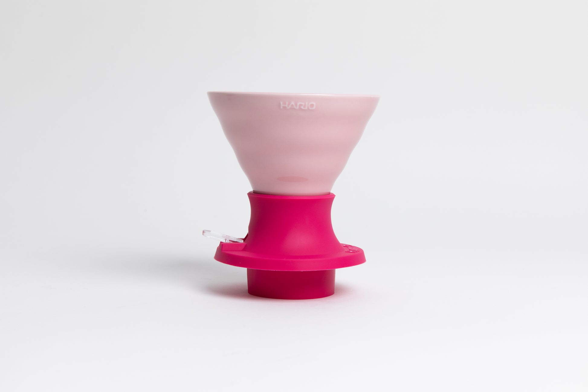 Cone-shaped light pink ceramic dripper seated in a hot pink silicone base with clear plastic push switch on a white background.