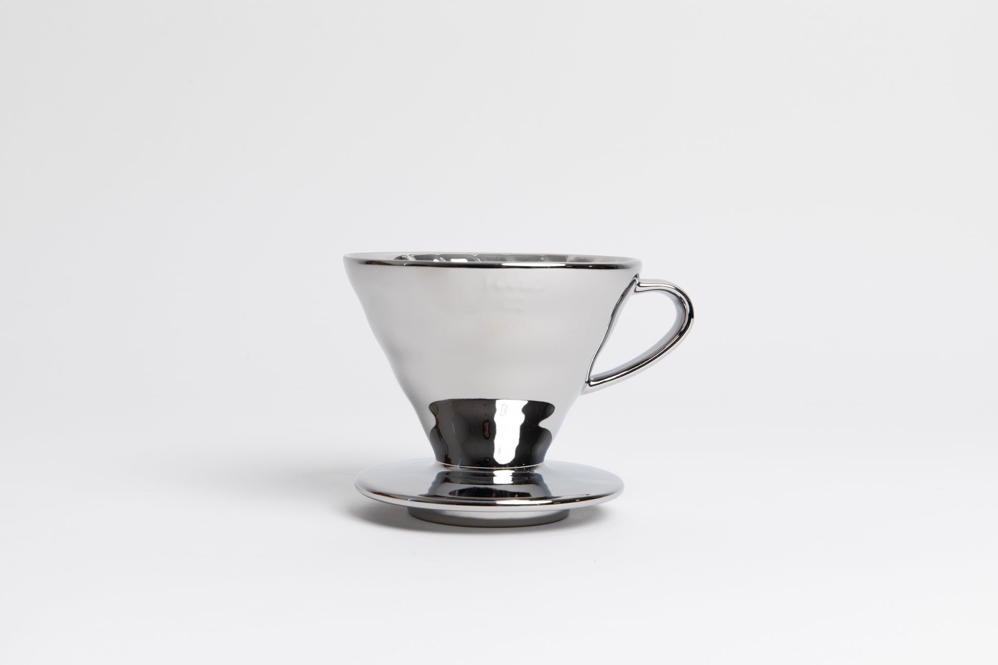 Metallic silver cone shaped ceramic coffee dripper with handle and round base. Set on white background