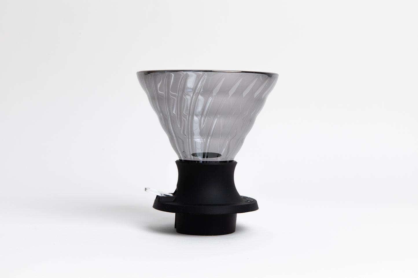 large cone-shaped clear black glass coffee dripper in a black silicone base with clear plastic push switch. set on a white background