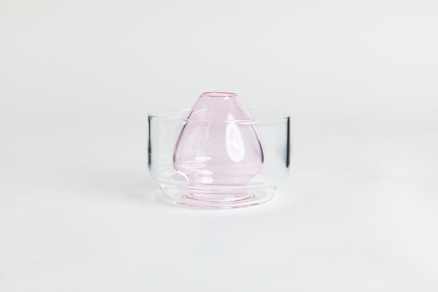 Dome-shaped pink clear glass matcha whisk holder with a smooth, tapered form, placed inside a clear glass base. Displayed on a white background with 'Hario' branding