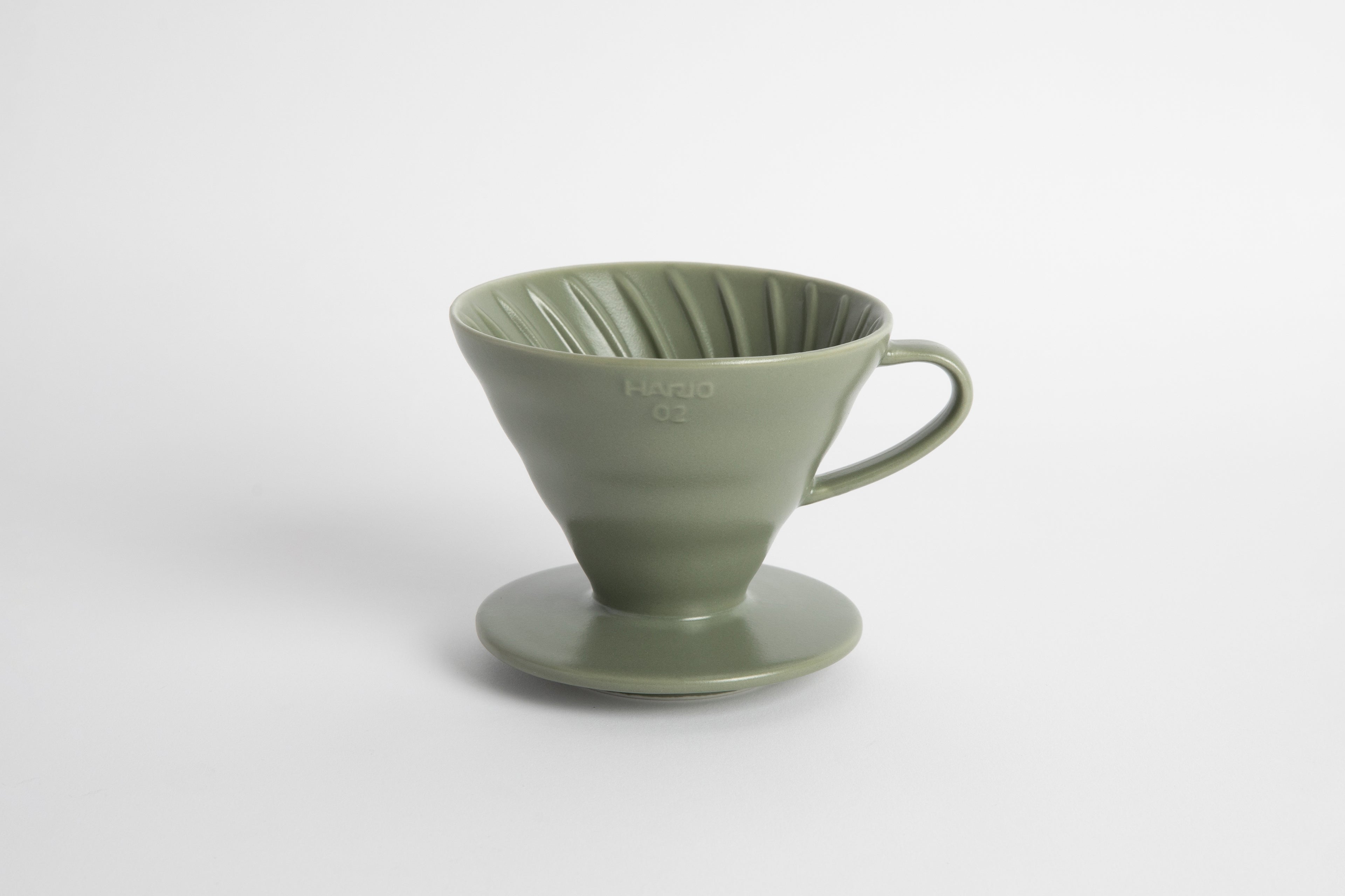 &quot;Oil Green&quot; sage colored 60 degree cone shaped ceramic coffee dripper with handle and round base. Spiral ribbed on the inside cone. Set on white background