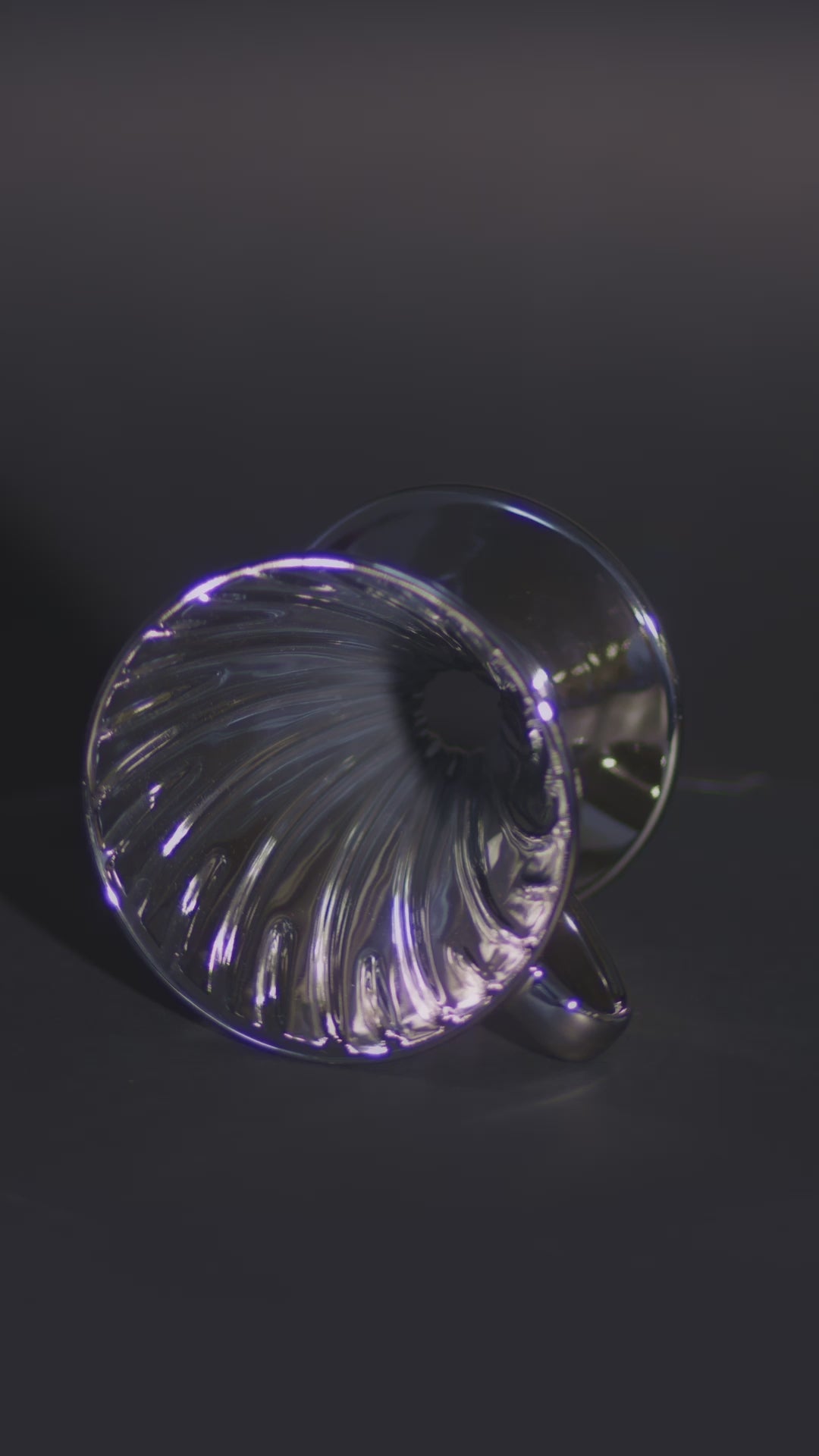 A metallic silver cone lying on its side, spinning to showcase the ribbed interior design.