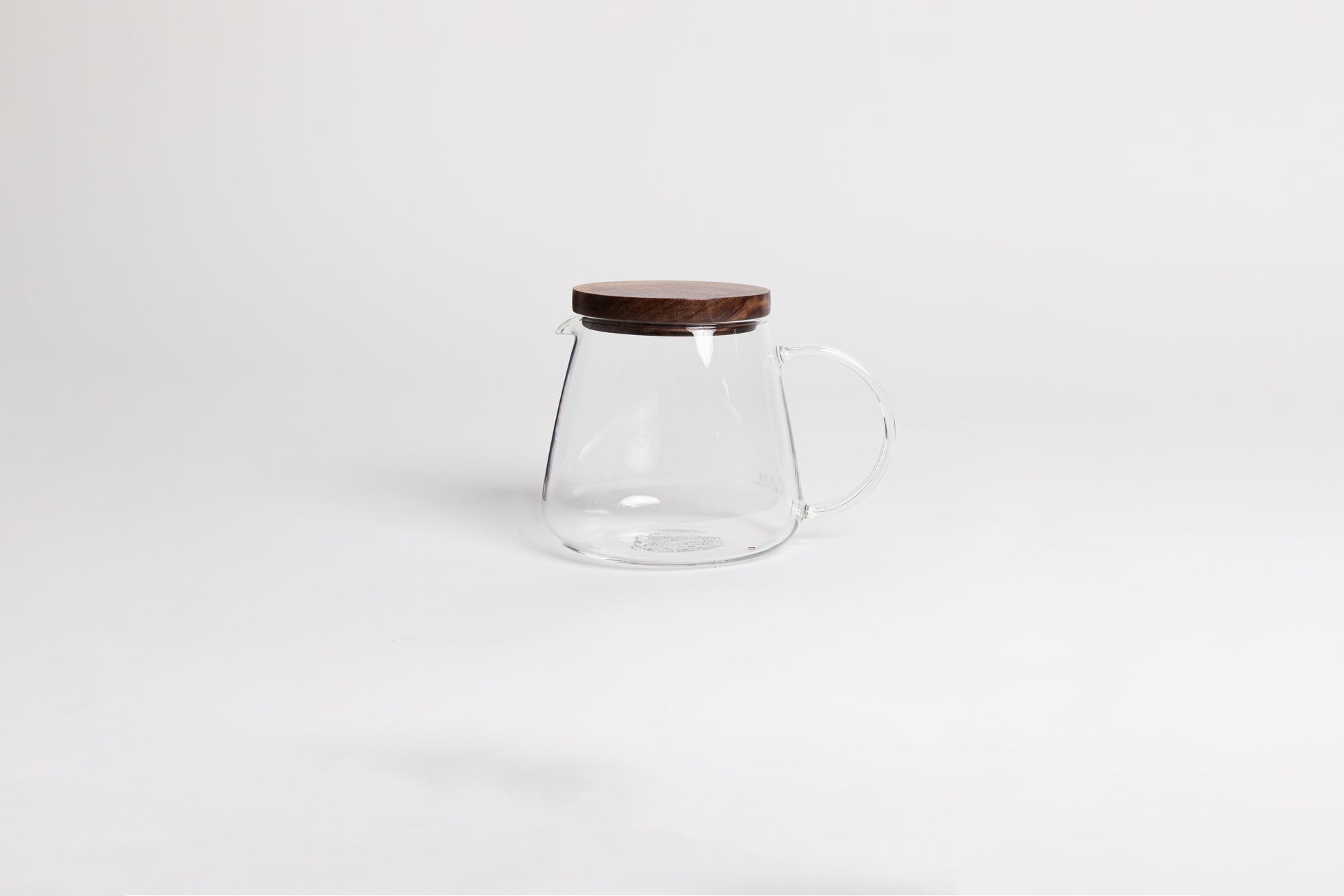 tulip shaped glass decanter with glass handle and spout. Topped with a walnut wood lid. set on a white background.