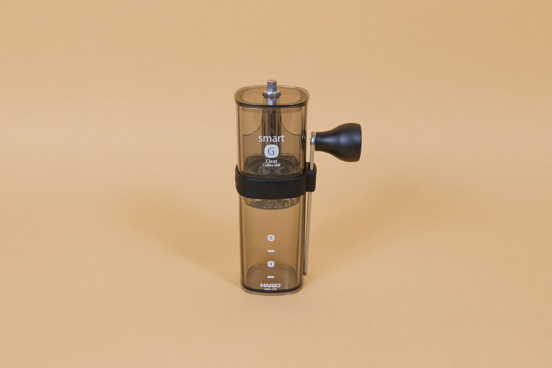 Dark clear transparent plastic coffee mill with a slim metal handle and knob attached on side