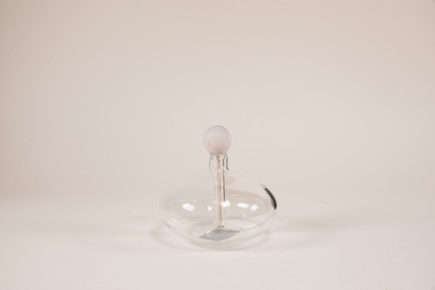 Oval shaped glass diffuser with natural wood wand and round knob.