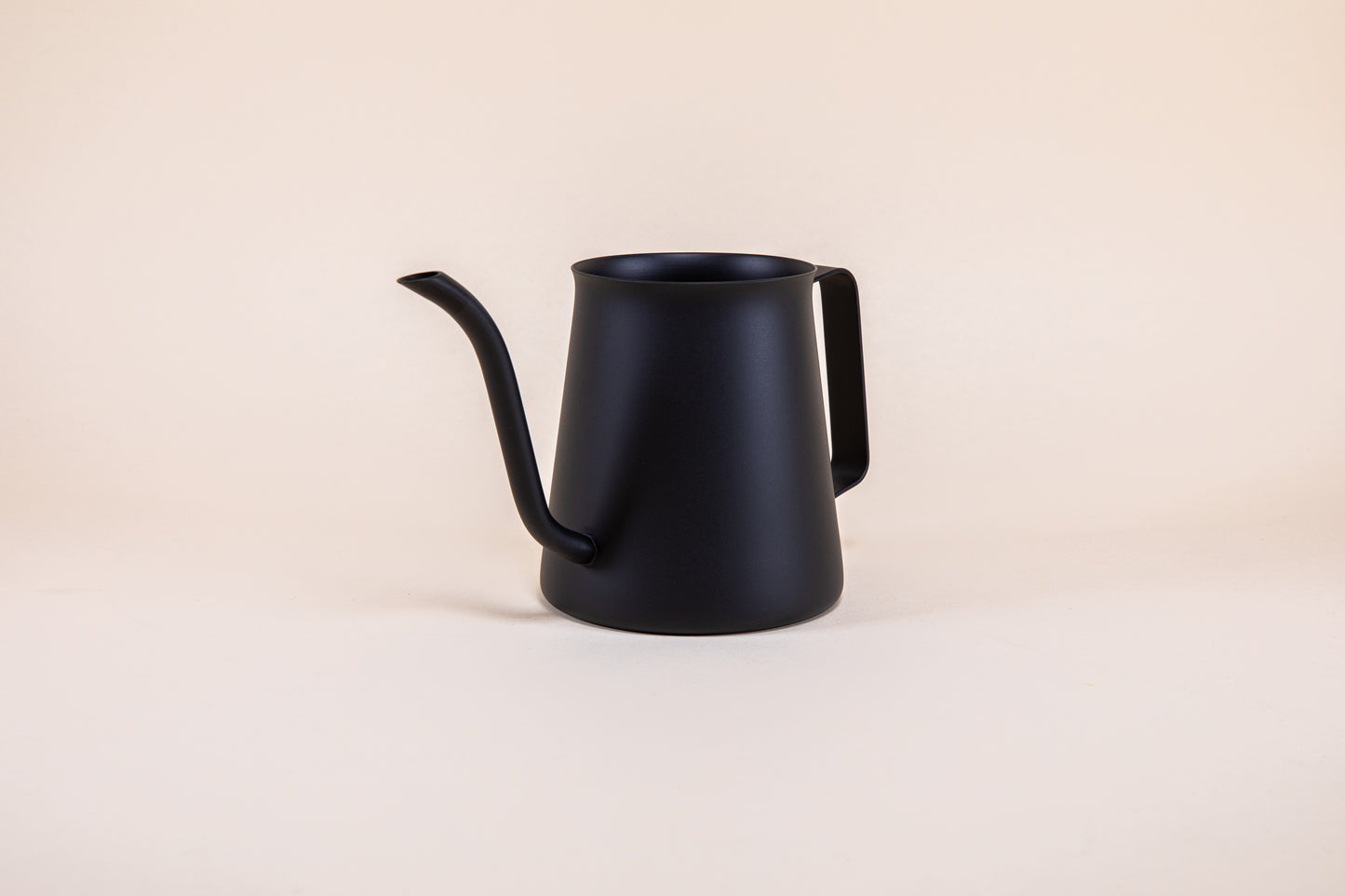All black metal kettle with flared top, gooseneck spout, and handle on a light background.