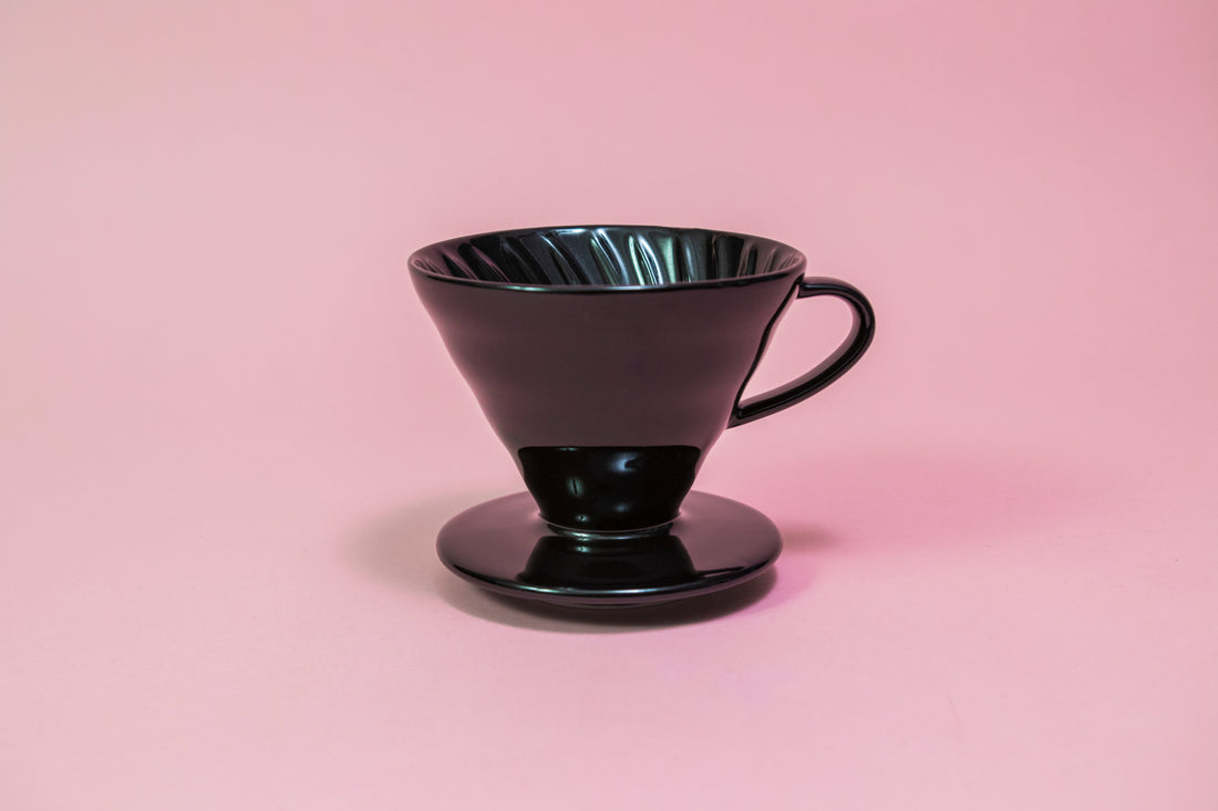 Black conical ceramic coffee dripper with handle and round base.