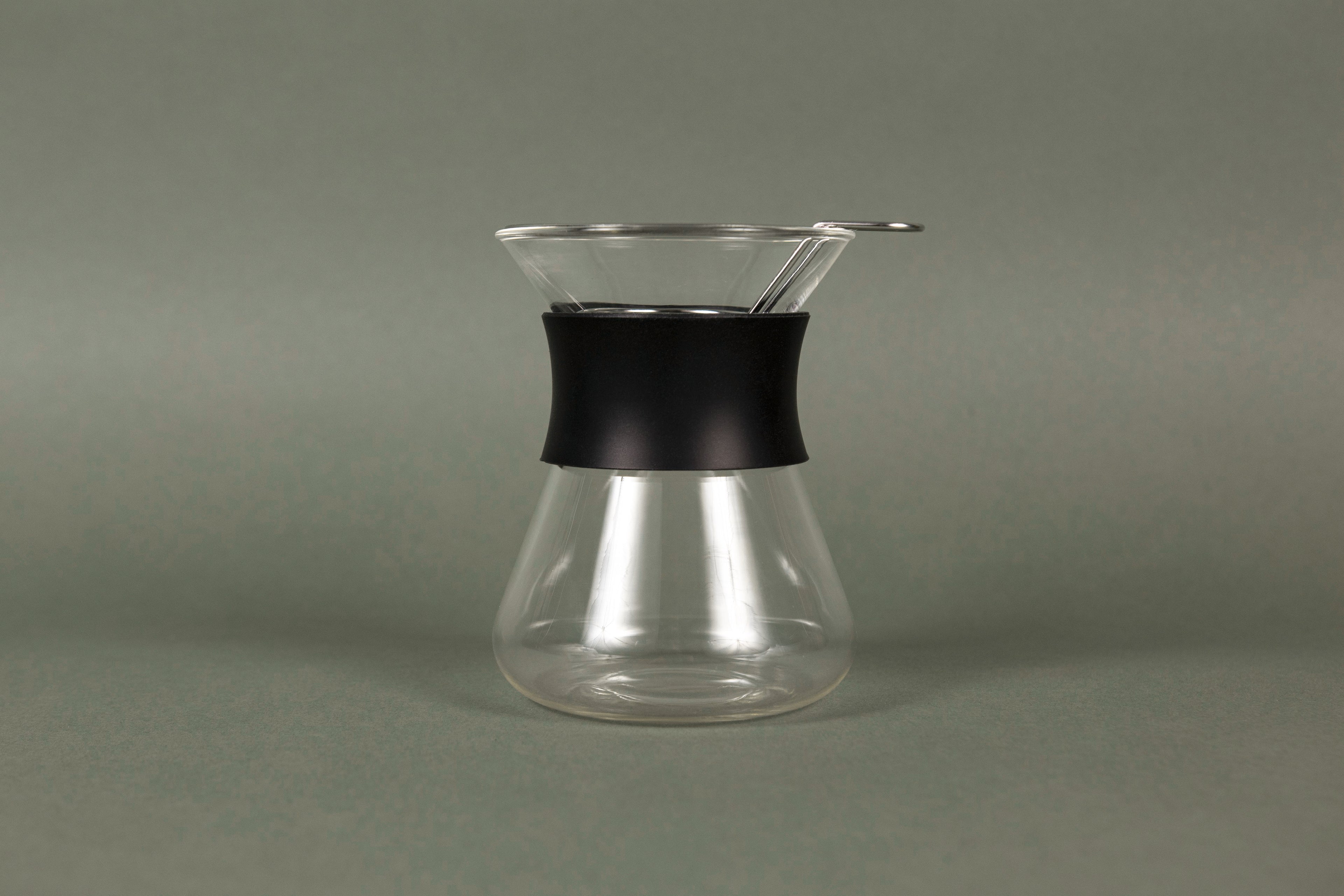 Hourglass shaped glass server with stainless steel wire dripper and black silicone rubber band.