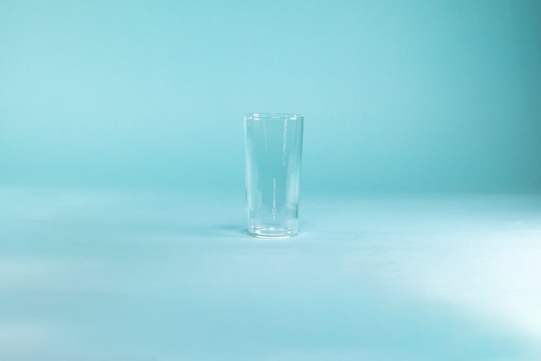 Thin, tall glass tumbler against a blue background.