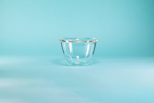 Glass mixing bowl on a blue background.