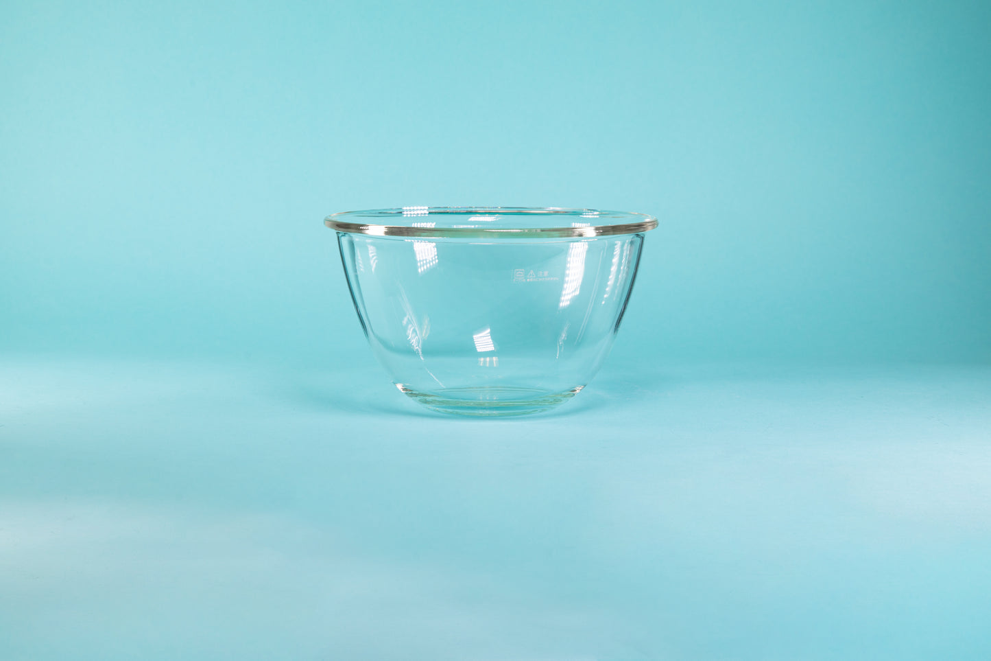 Glass mixing bowl on a blue background.