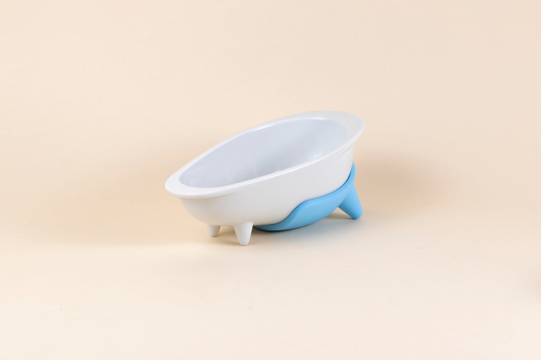White glazed porcelain dog bowl shaped like a bathtub with mint blue silicone non-slip mat.