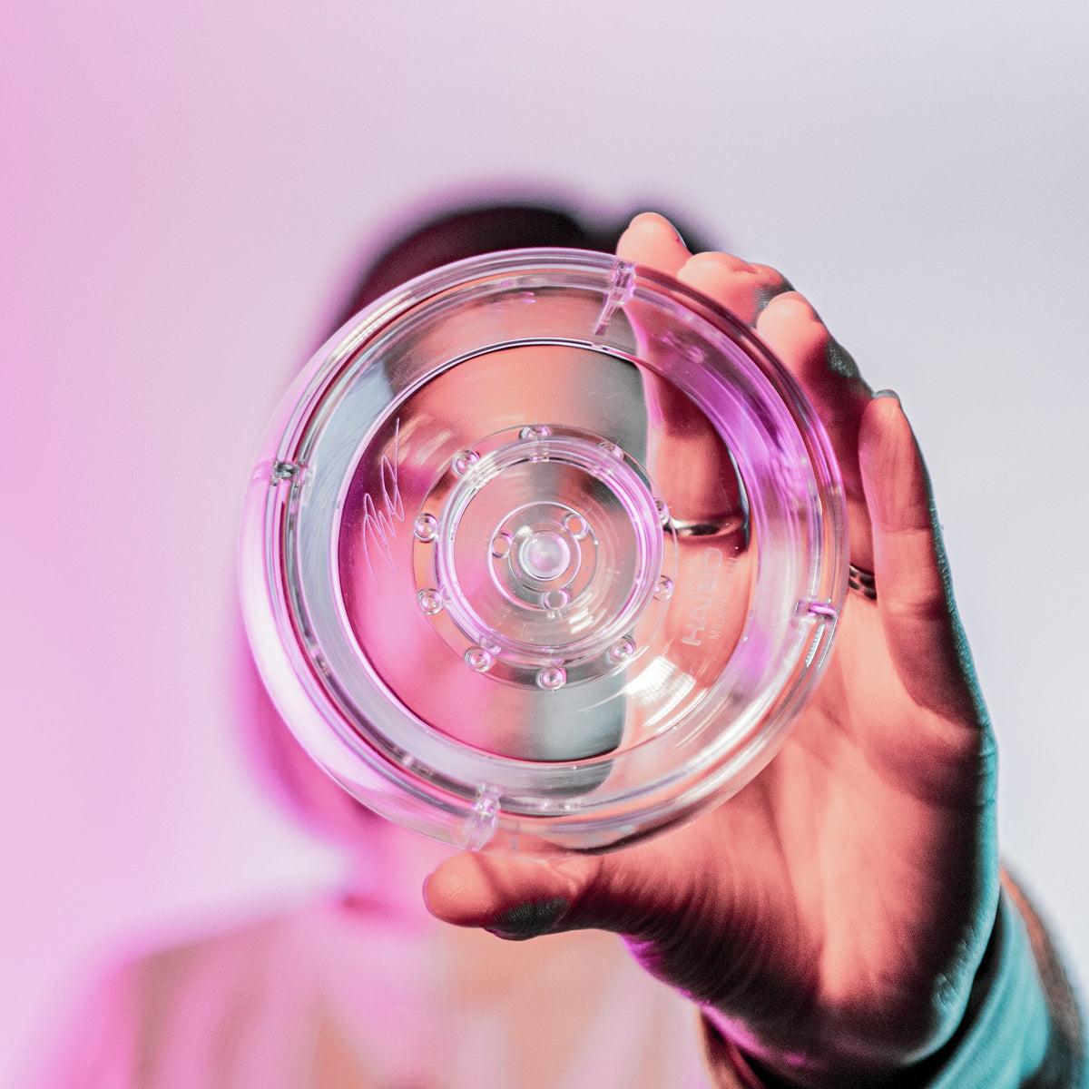 Model holding a clear plastic ring with interior smaller ring and holes for liquid to drain through.