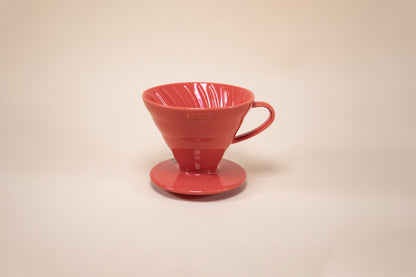 Red cone shaped ceramic coffee dripper with handle and round base.