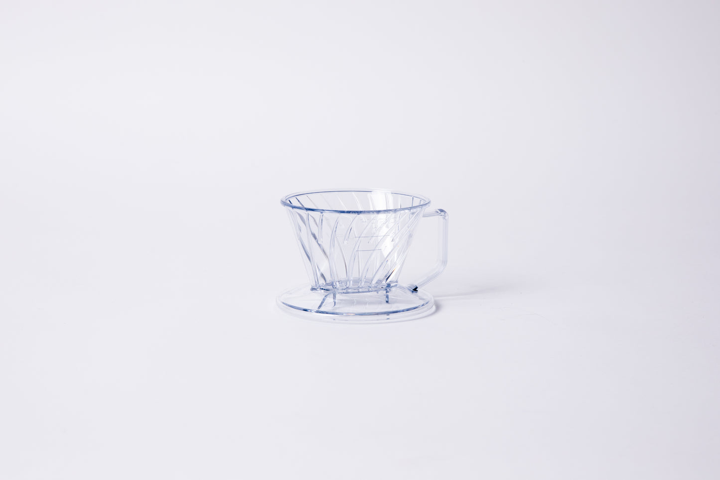 Clear plastic ribbed cone shaped dripper with a flat bottom base and handle. Set on a light gray background