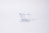 Clear plastic ribbed cone shaped dripper with a flat bottom base and handle. Set on a light gray background