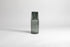 Transparent gray carafe with matching glass cup flipped upside down on carafe top of carafe. Set on a light gray background