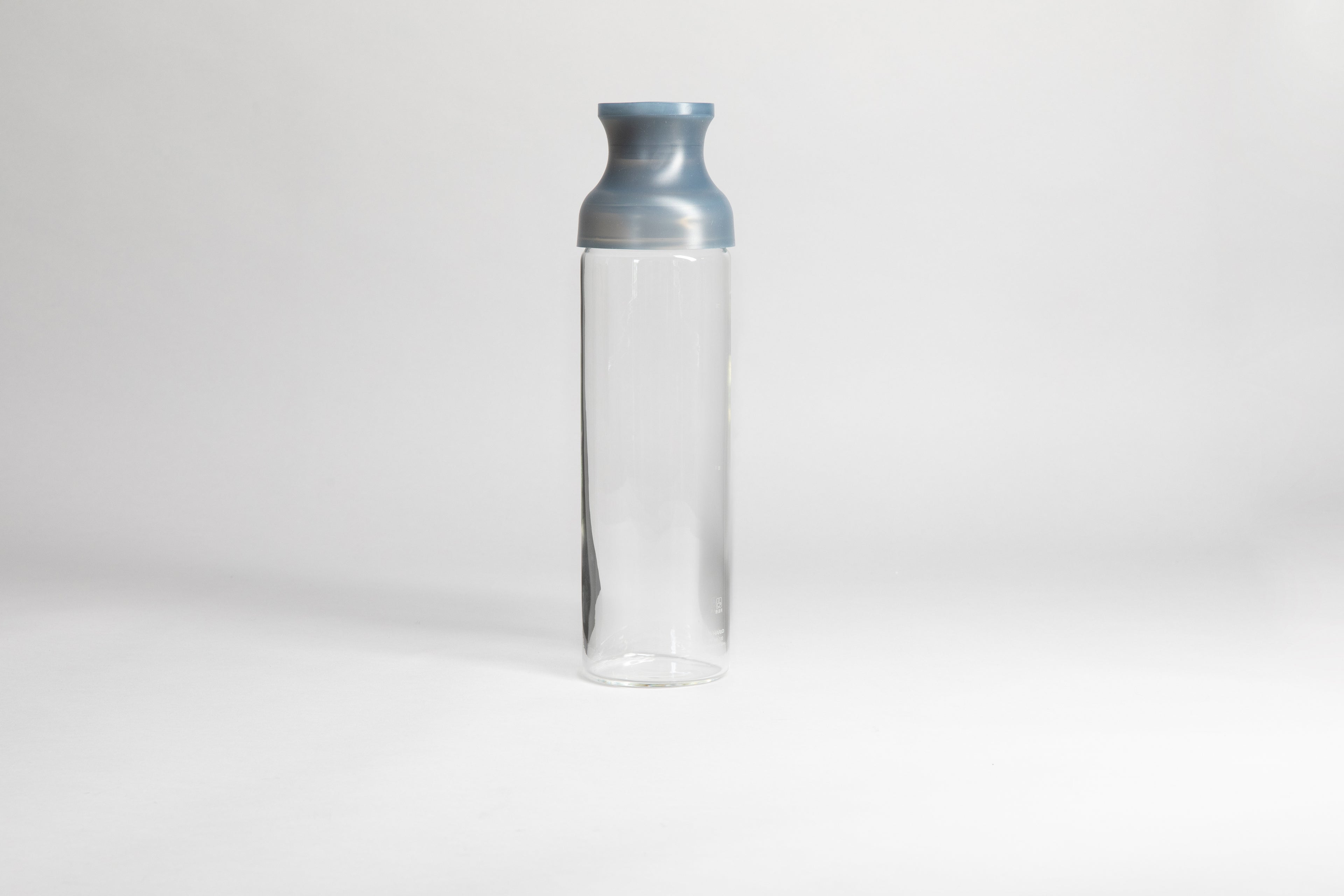 Cylindrical glass bottle with a clear grey silicone wide mouth spout. set on a white background
