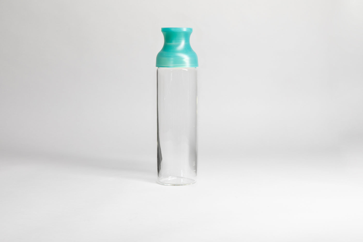 Cylindrical glass bottle with a clear green silicone wide mouth spout. set on a white background