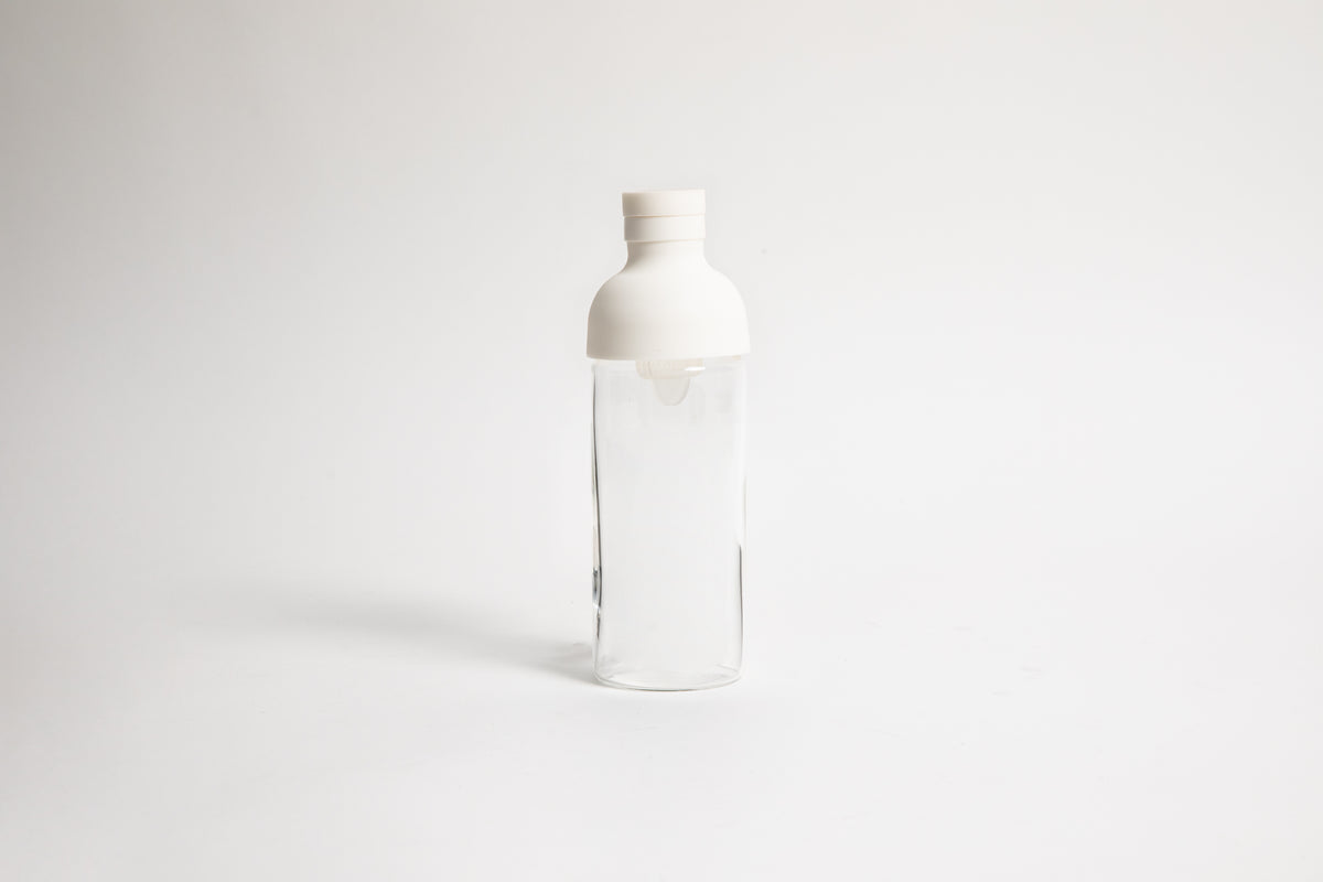 A clear glass bottle with an white silicone cap, shown on a  white background.