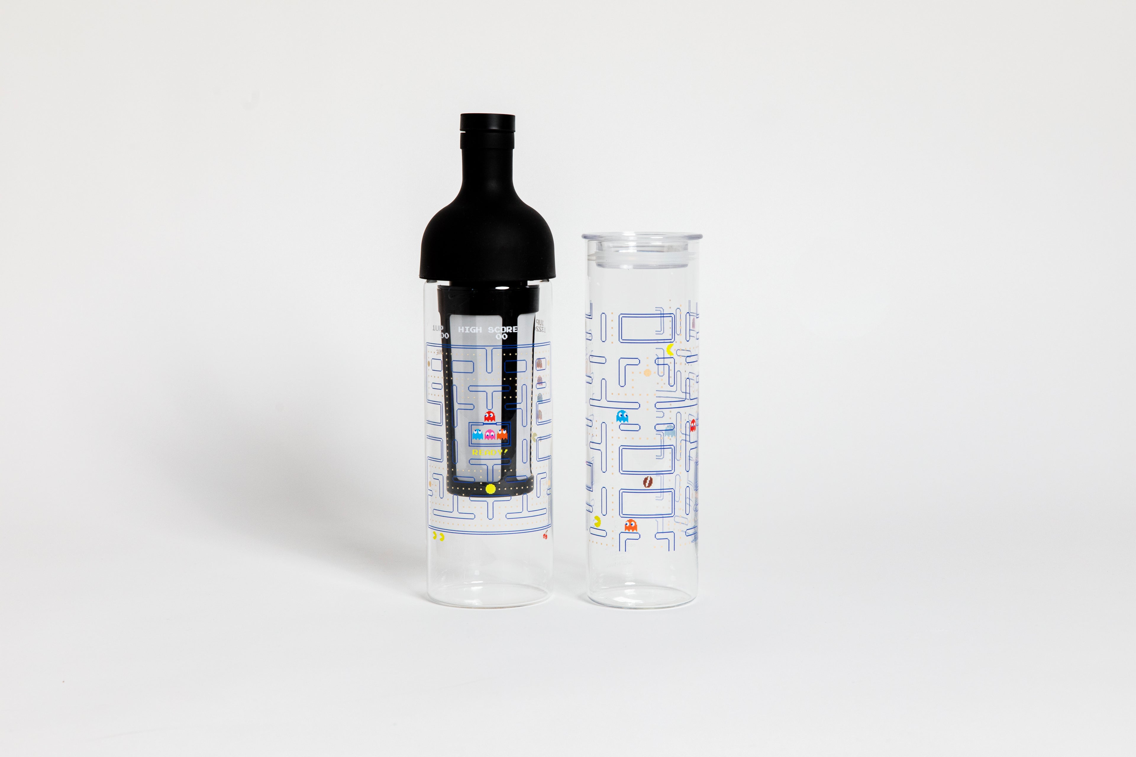 Tall glass container and black nylon mesh coffee filter, with black rubber wine bottle shaped top. Glass decorated with &quot;pac-man&quot; blue maze game with colorful ghosts and an yellow, circular figure with a wedge-shaped mouth.