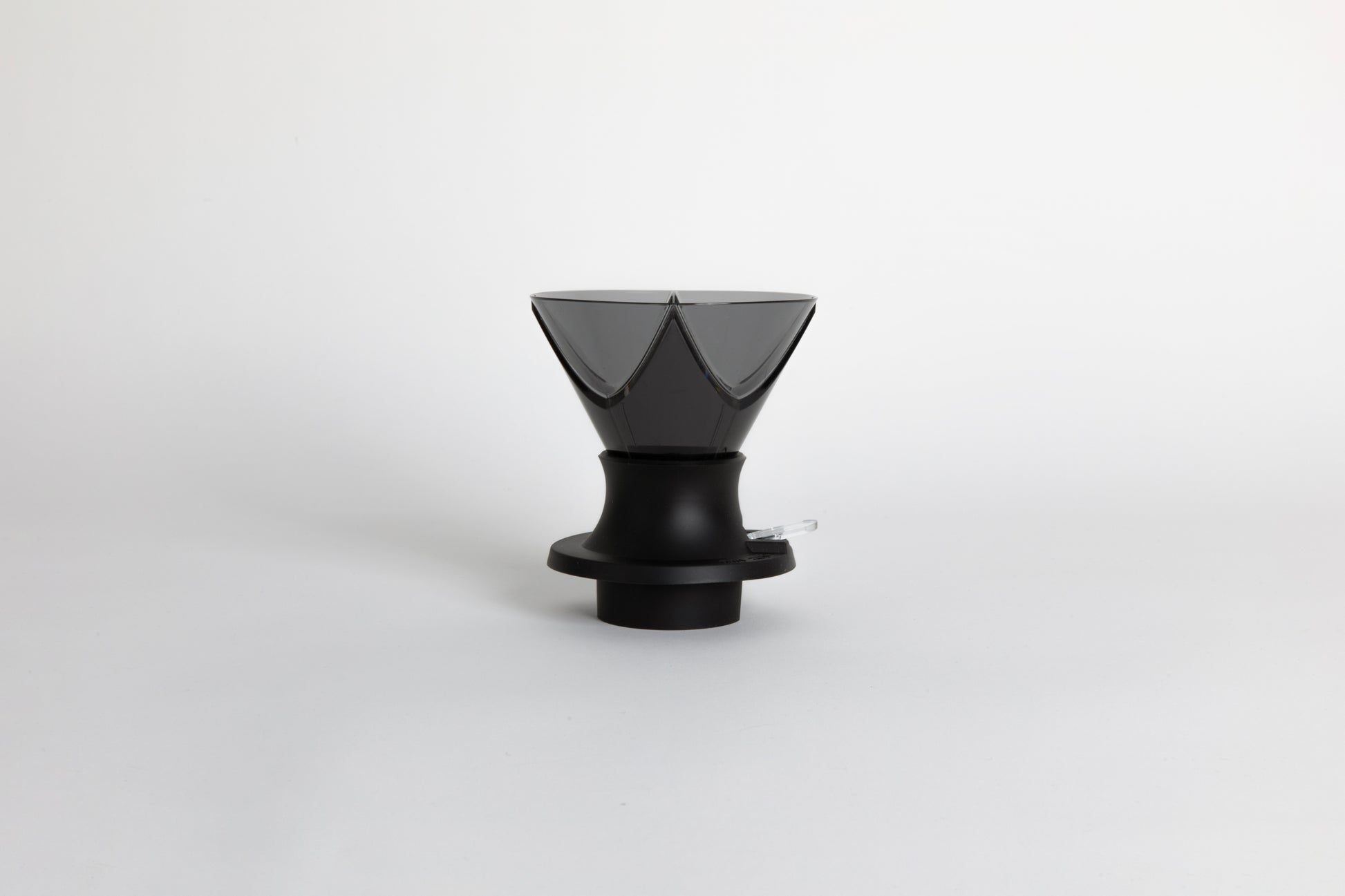 Translucent black plastic cone shaped dripper with bezier ridges in a black silicone base with clear plastic push switch