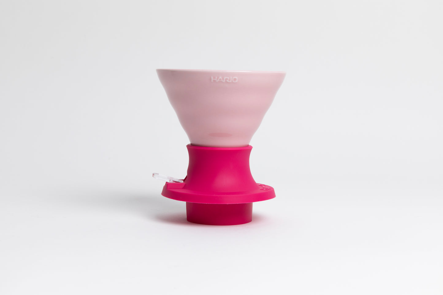 Cone-shaped light pink ceramic dripper seated in a hot pink silicone base with clear plastic push switch on a white background.