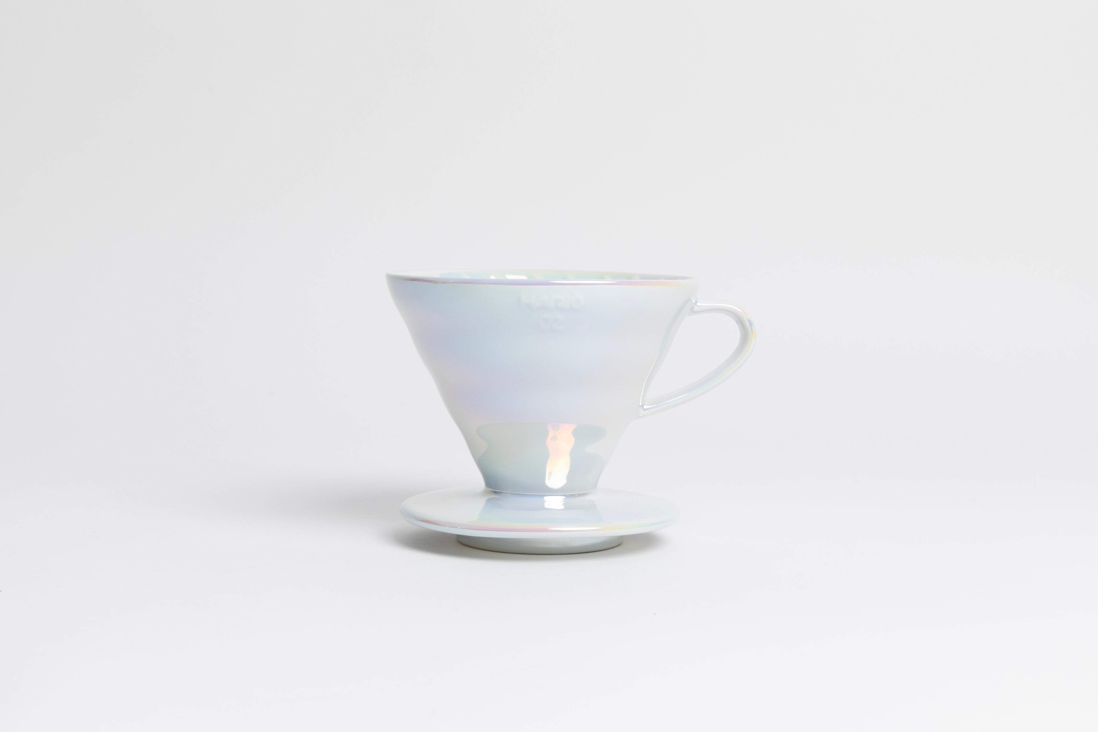 Iridescent cone shaped ceramic coffee dripper with handle and round base. Set on white background