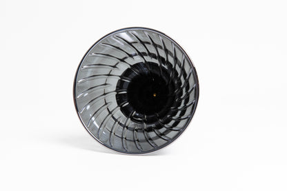 clear black conical ceramic coffee dripper  lying on its side showing ribs and  drip hole