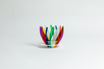 Transparent rainbow in the colors red, blue, green, white, orange, purple and yellow pedals in a spiral shape on a transparent black base on a white background.