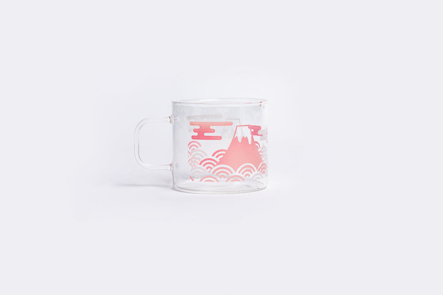 Clear glass mug with pink mountain and wave design on a white background