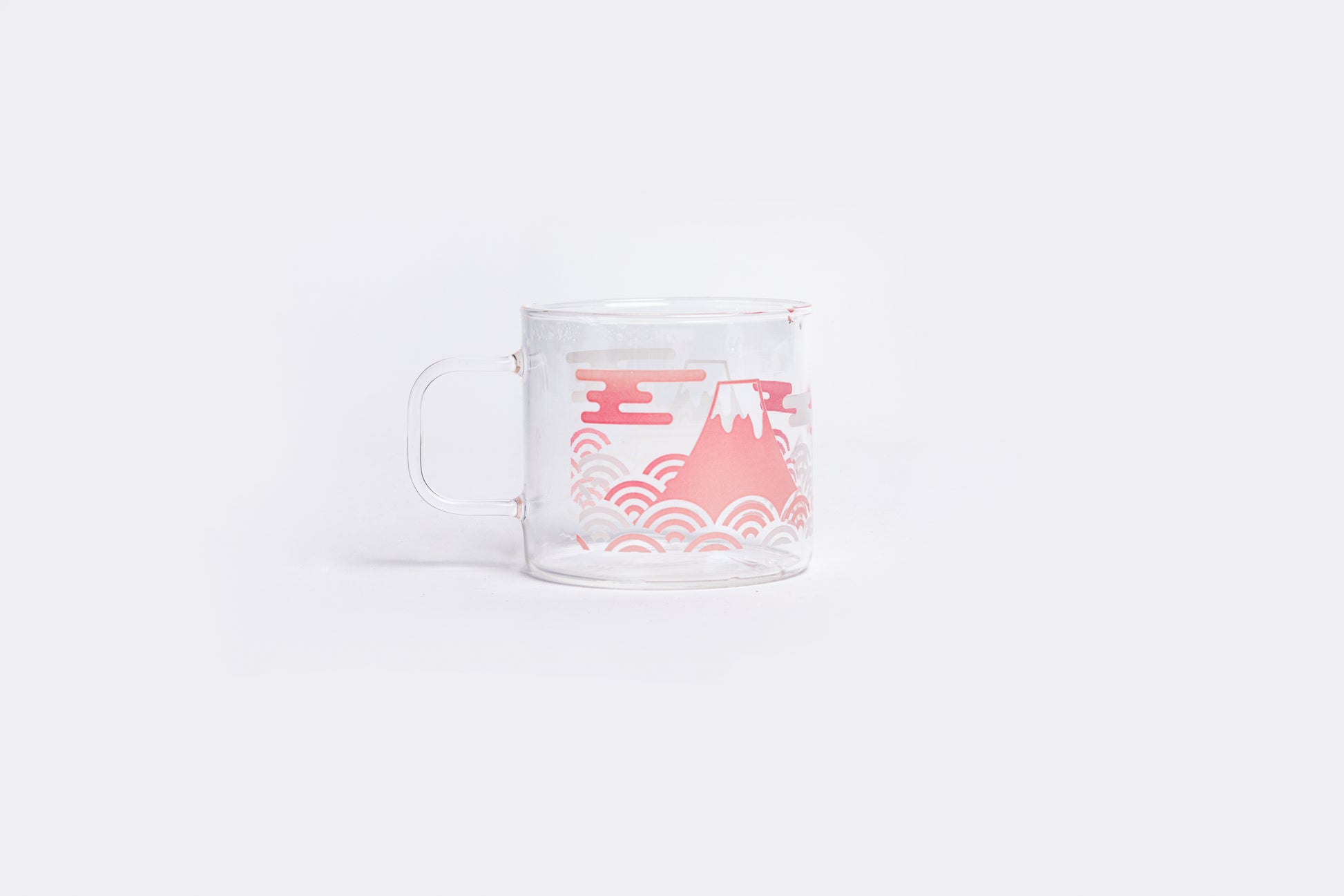 Clear glass mug with pink mountain and wave design on a white background