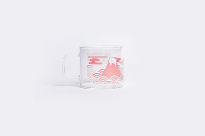 Clear glass mug with pink mountain and wave design on a white background