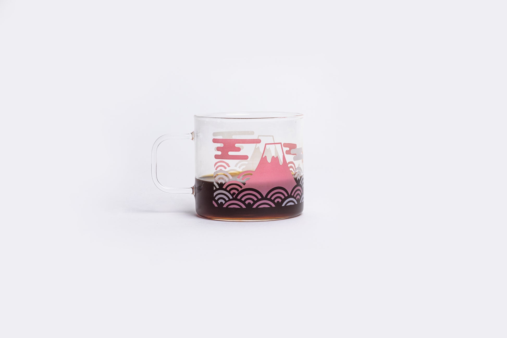 coffee in a clear glass mug with a white and pink design on a white background