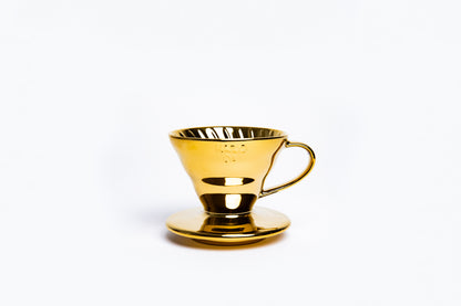 Gold cone coffee dripper with handle on a white background