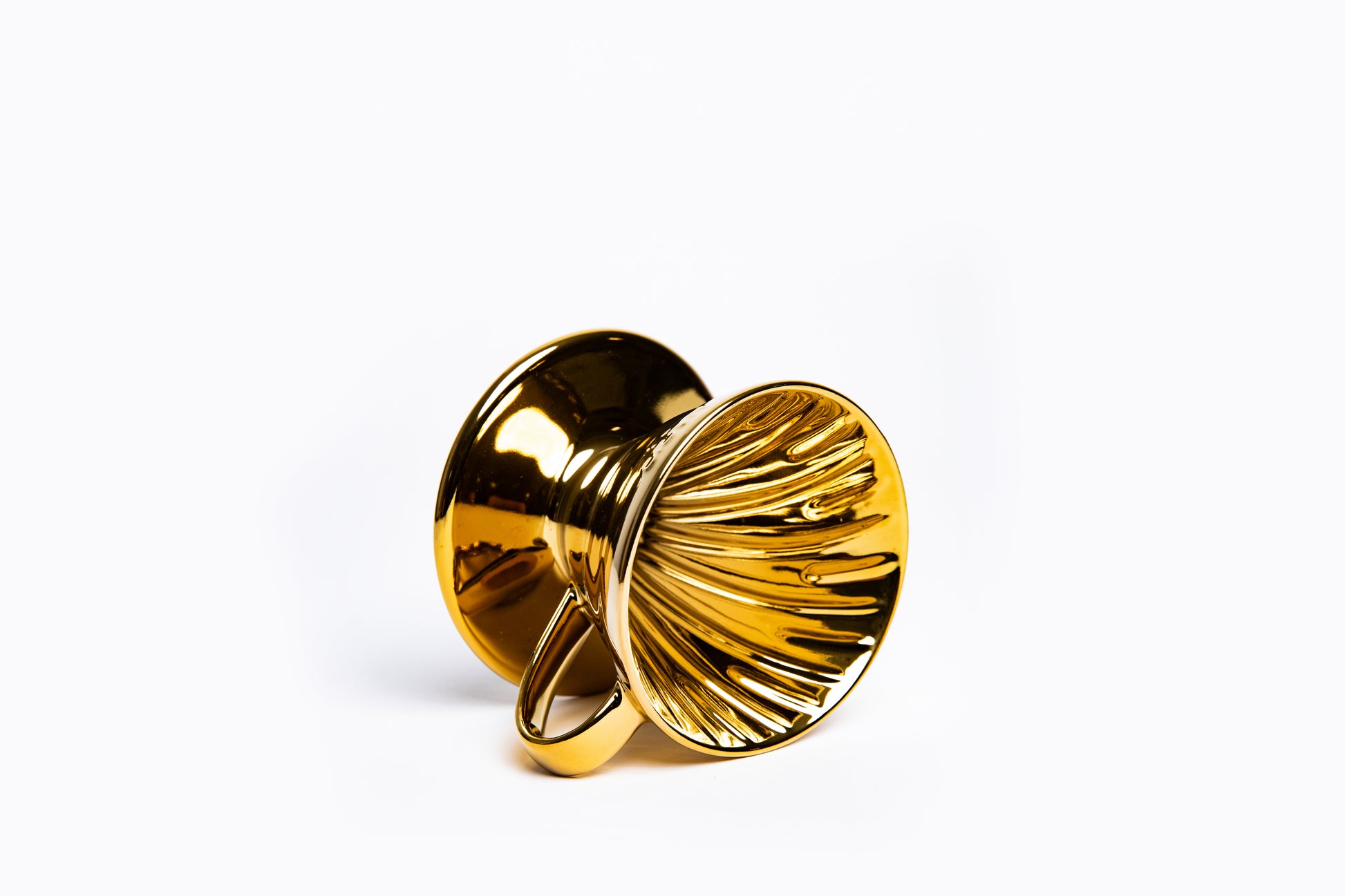 Gold cone coffee dripper with handle with ribbed interior on a white background