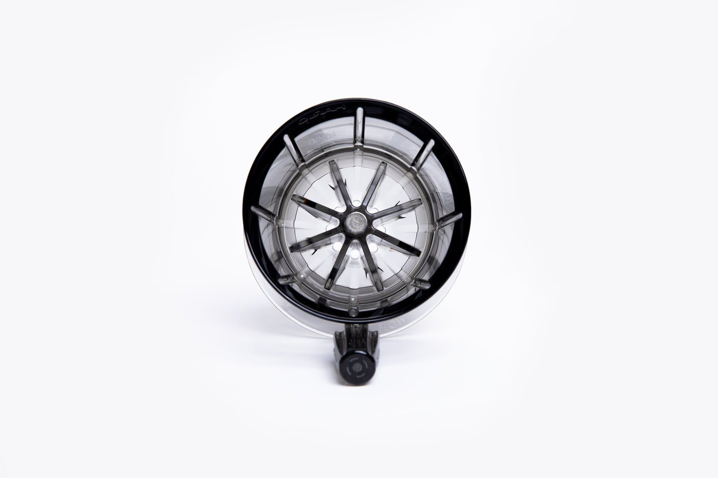 Top view of a clear gray pour-over coffee dripper with internal ridges and a center hole on white background