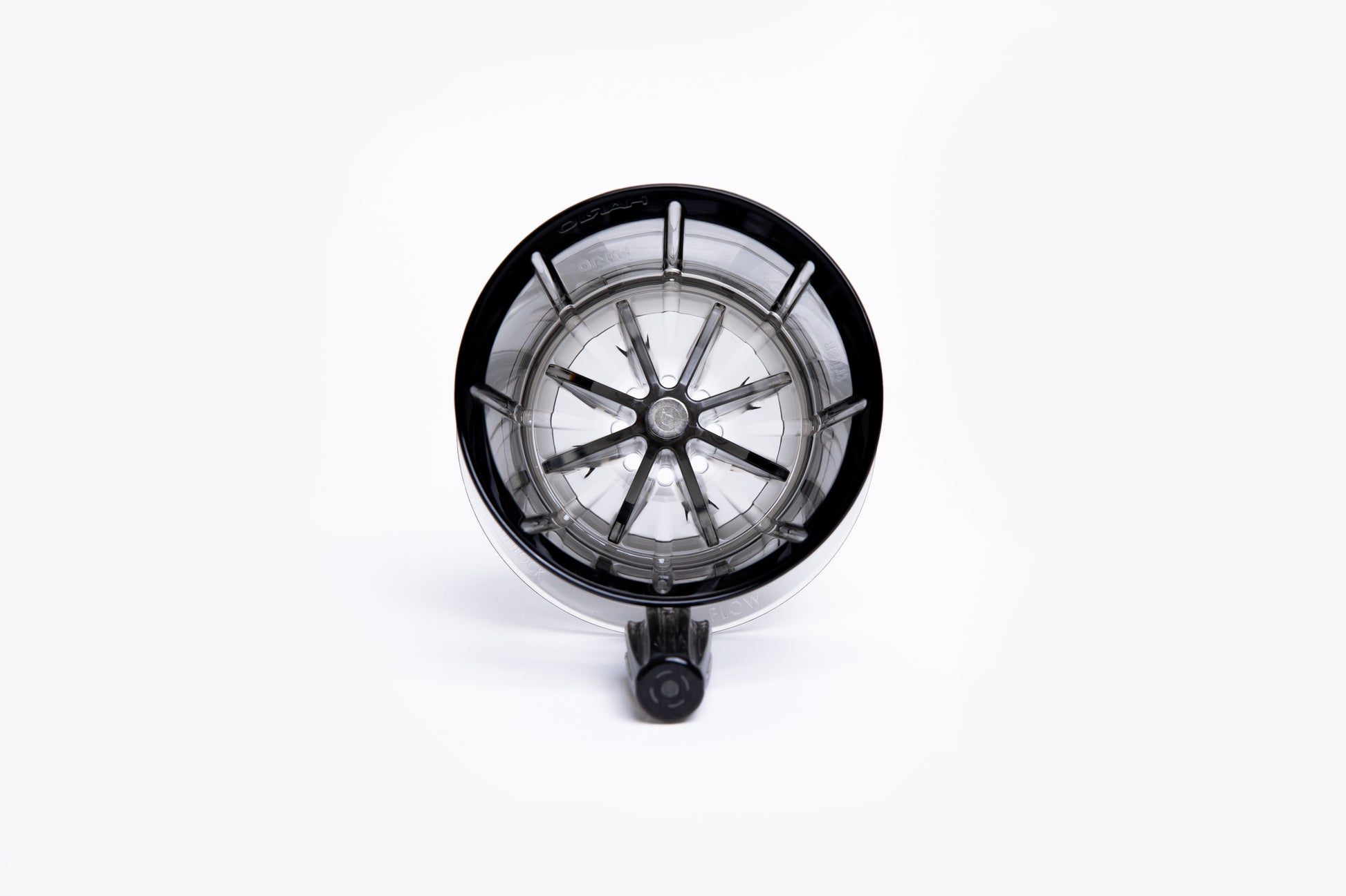 Top view of a clear gray pour-over coffee dripper with internal ridges and a center hole on white background