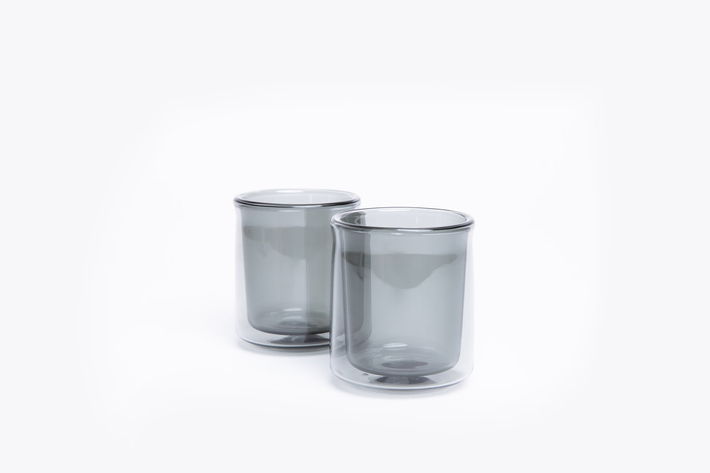 Two smoked glass tumblers on a white background