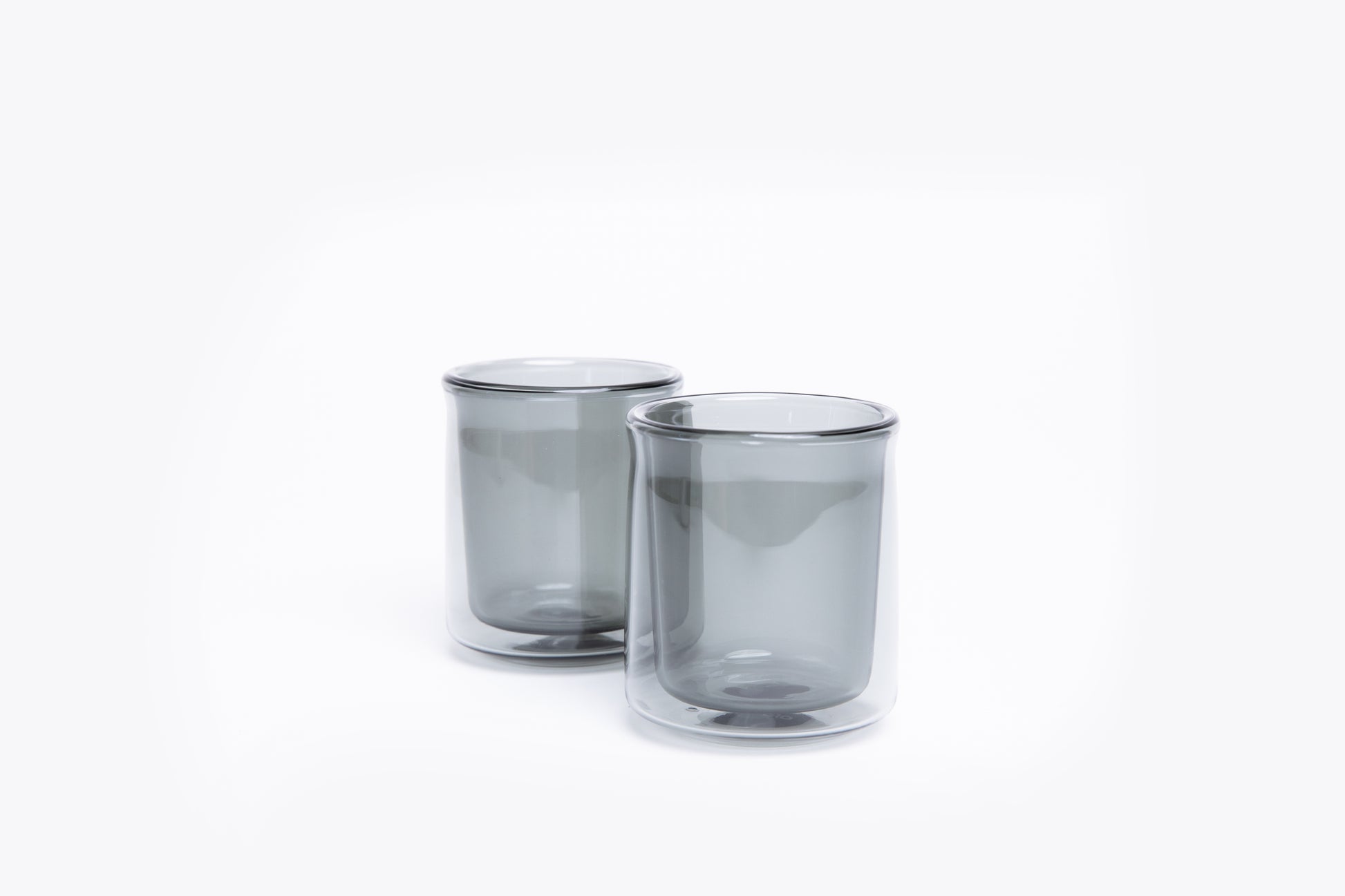 Two smoked glass tumblers on a white background