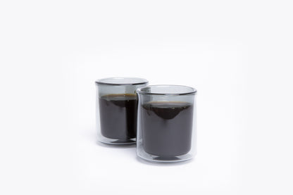 Two clear glass cups filled with black liquid on a white background