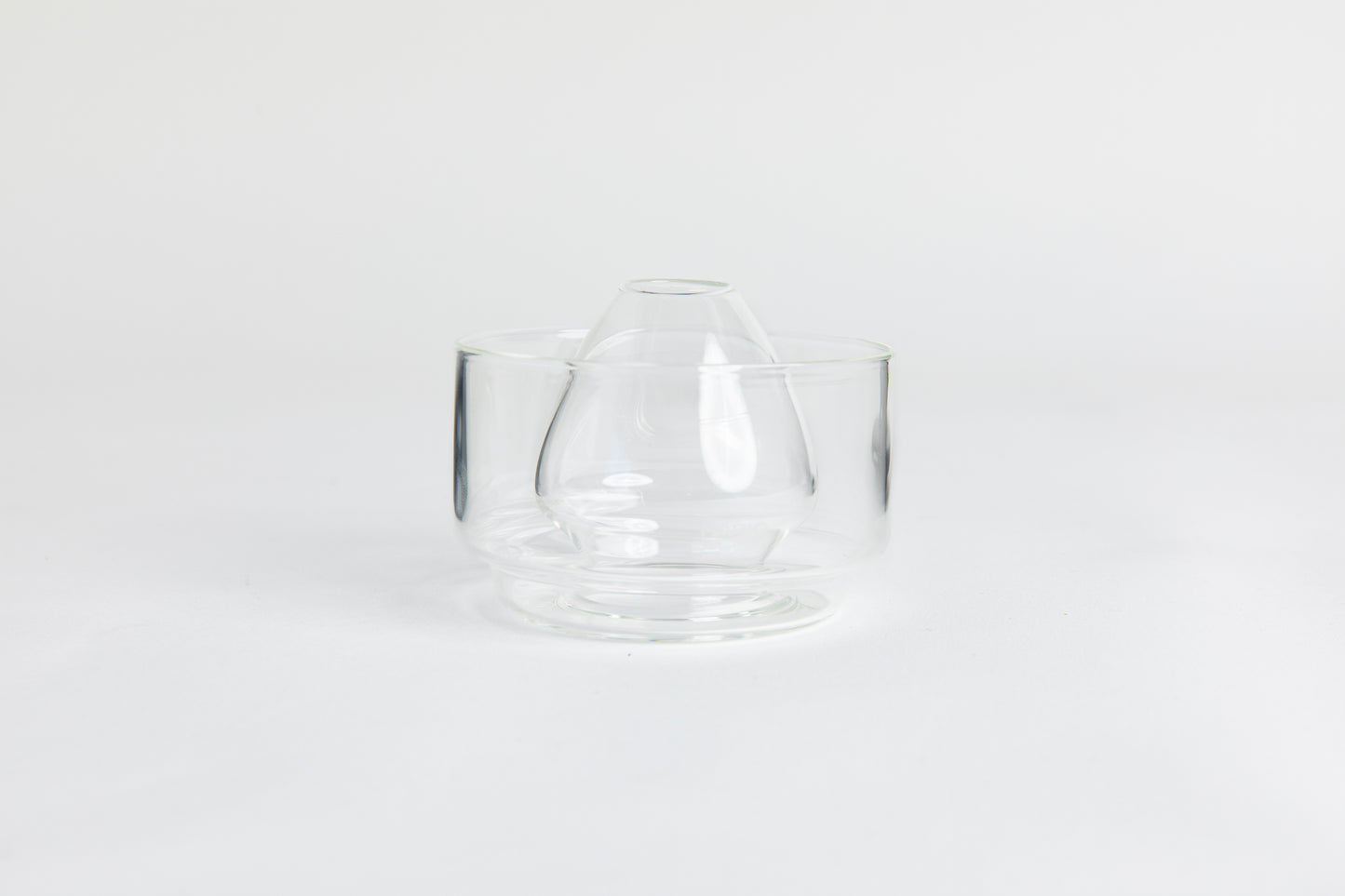 Dome-shaped clear glass matcha whisk holder with a smooth, tapered form, placed inside a clear glass base. Displayed on a white background with 'Hario' branding