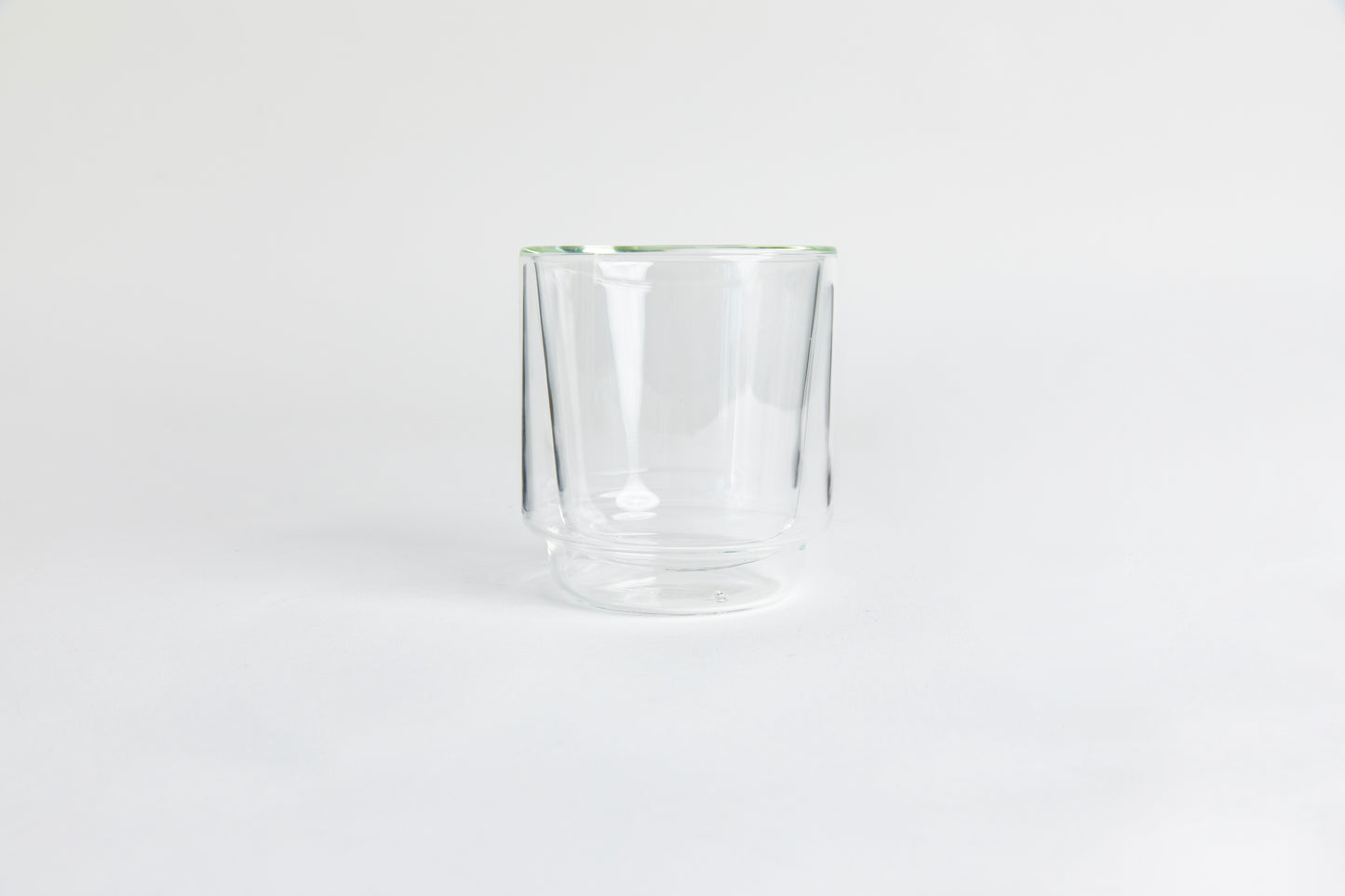 A clear double-walled glass cup. set on a white background