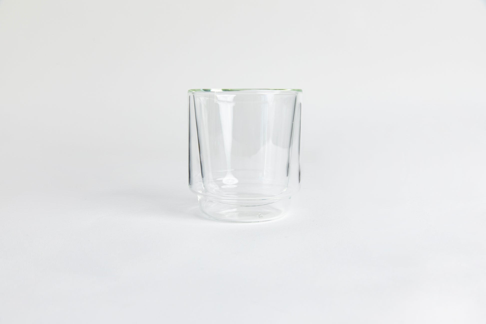 A clear double-walled glass cup. set on a white background