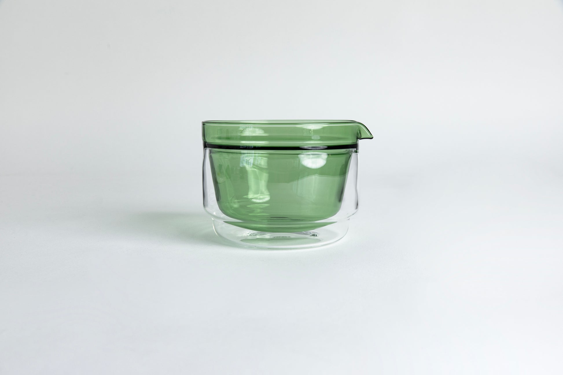 Double-walled glass cup with green interior. set on a white background.