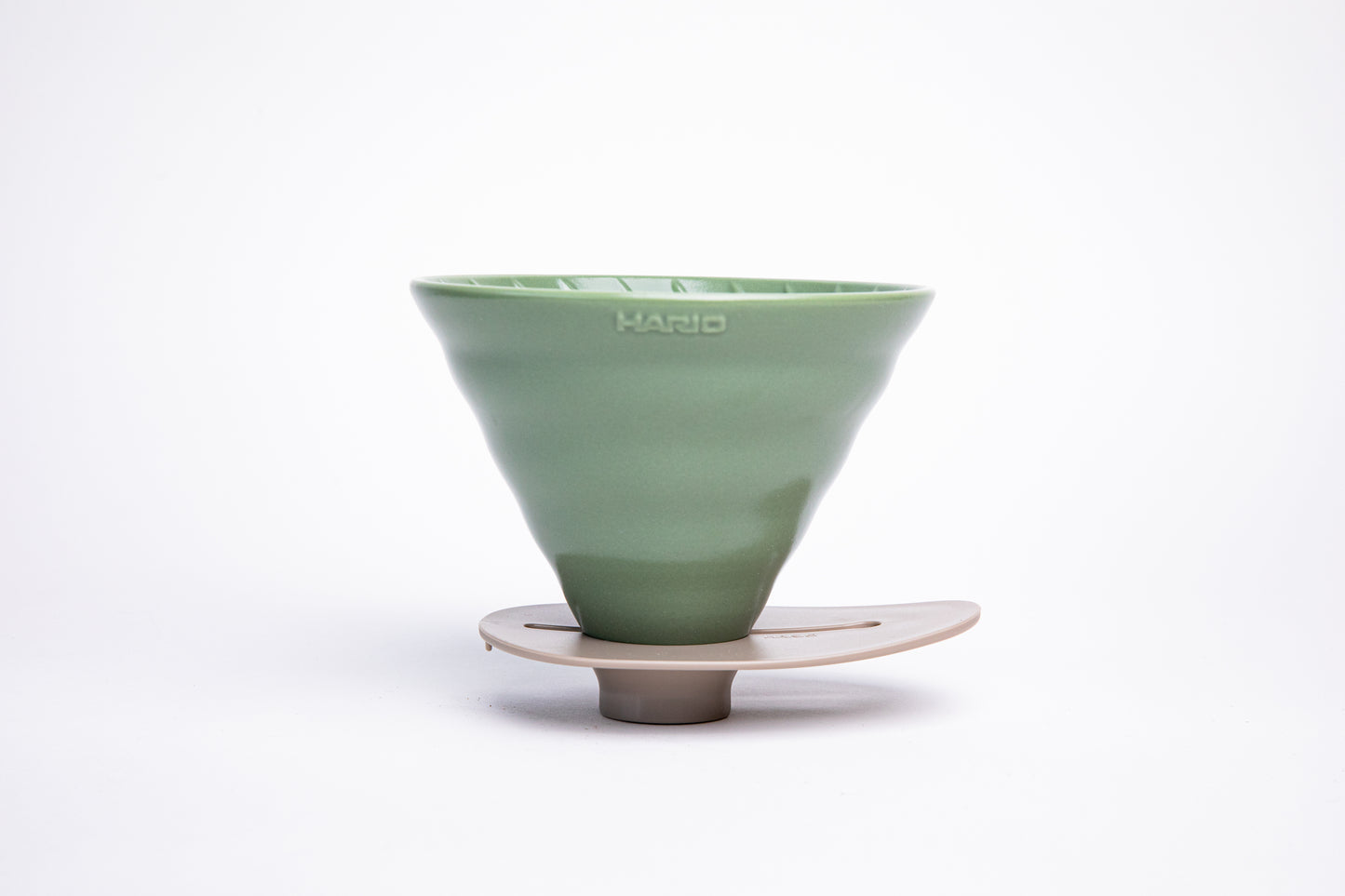 green ceramic cone dripper on a ivory base on a white background