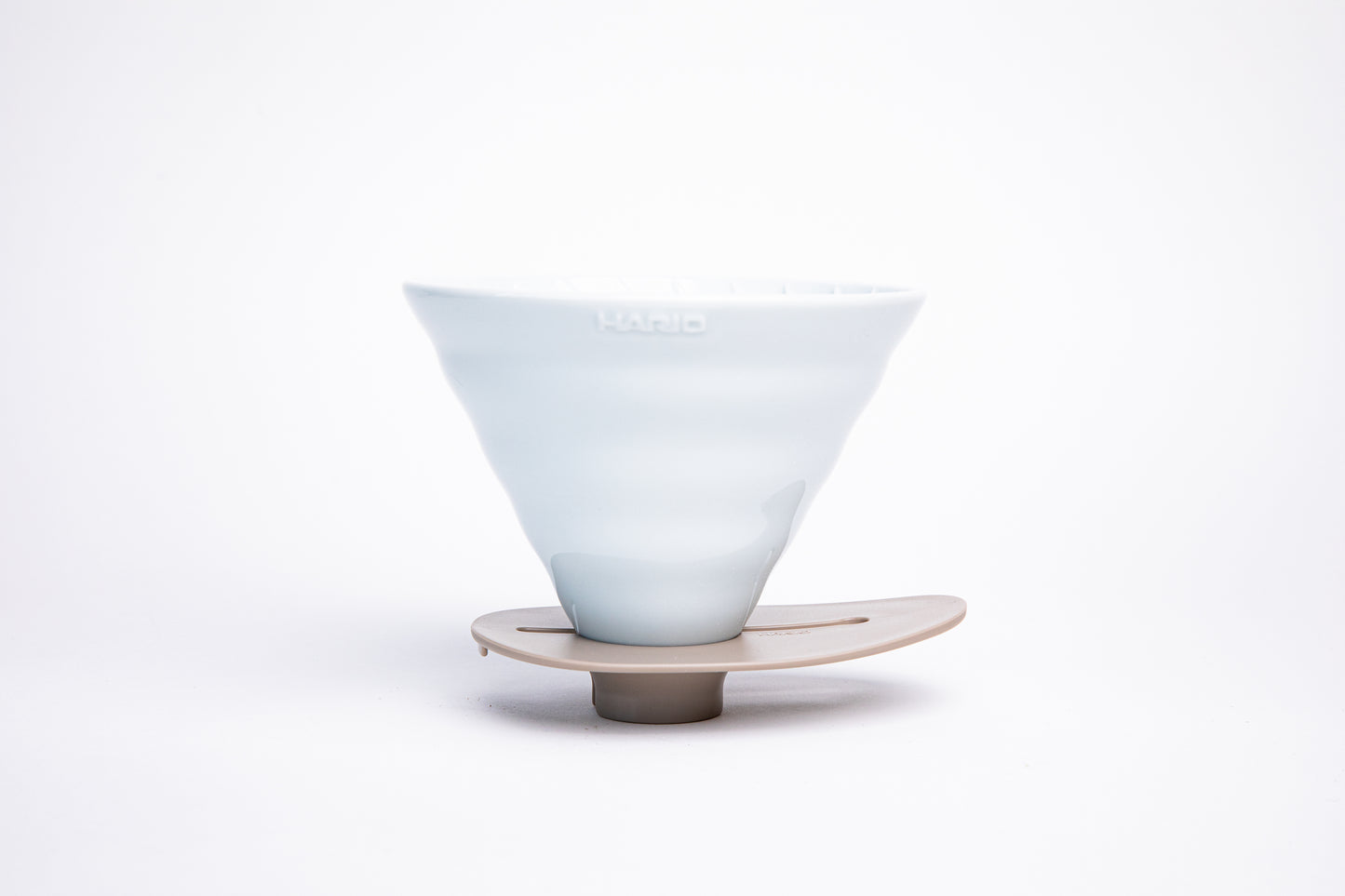 white ceramic cone dripper on a ivory base on a white background